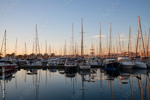 Yacht parking in the marina at sunset. Sea bay with yachts at sunset. Moored yachts. Marina, port. reflection of boat masts in sea water at sunset. Torrevieja, Alicante, Spain © Ketrin