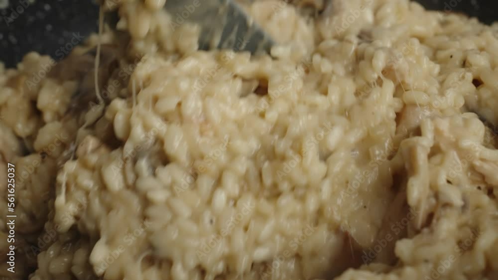 Process of cooking risotto with mushrooms. Cook mixes arborio rice with stretching parmesan cheese in frying pan, close up. Italian cuisine dish Process of cooking risotto with mushrooms. Cook mixes arborio rice with stretching parmesan cheese in frying pan, close up. Italian cuisine dish