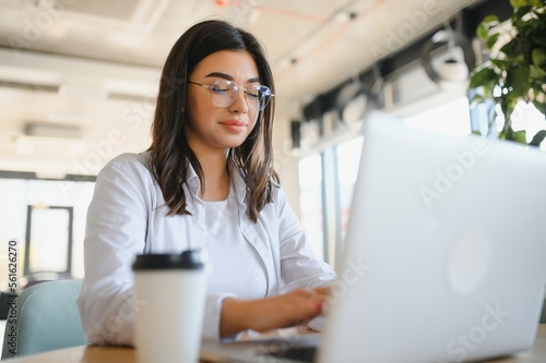 Excited woman reading good news on laptop sitting in a coffee shop terrace