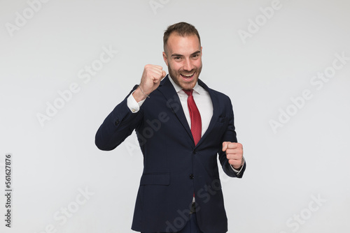 excited young businessman in suit holding fists up and celebrating