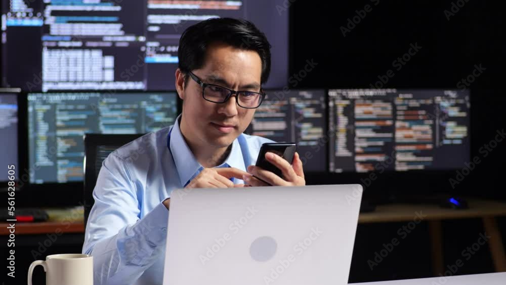 Asian Male Programmer Using Smartphone While Writing Code By A Laptop Using Multiple Monitors Showing Database On Terminal Window Desktops In The Office
Asian Male Programmer Using Smartphone While Writing Code By A Laptop Using Multiple Monitors Showing Database On Terminal Window Desktops In The Office
