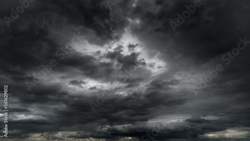 dark dramatic sky with black stormy clouds before rain or snow as abstract background, extreme weather, the sun shines through the clouds, high contrast photo