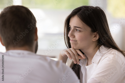 Pretty girl feeling boredom, doubt during dating. Bored young woman meeting with boyfriend in cafe, listening to man, sitting at table, touching chin, looking away, thinking, dreaming