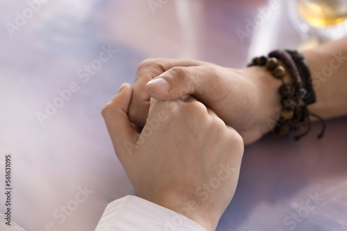 Young man holding female hands on tabletop  expressing love  care  sympathy  support. Romantic couple dating in cafe  touching arms  flirting. Close up cropped shot  high angle
