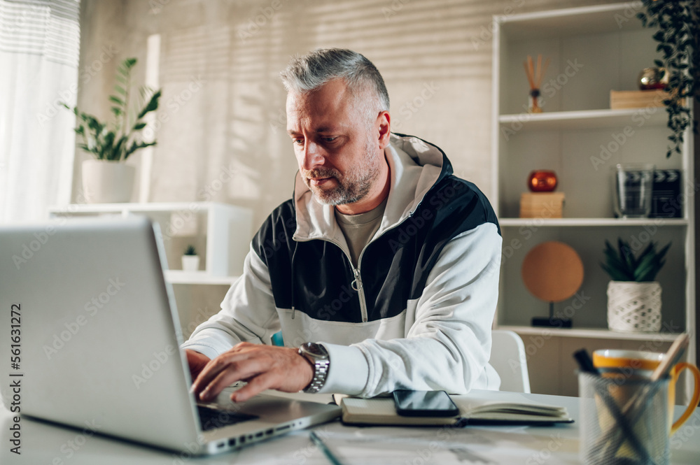 Middle aged man a laptop while working in a home office Middle aged man a laptop while working in a home office