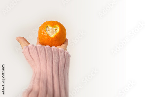 female hand holds, offers orange, beautiful composition with heart carved in citrus, concept of love, vitamins, healthy eating, healthy life, idea for design for Valentine's Day, Mother's Day, wedding