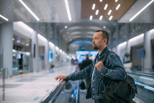 A man with a backpack moves to the gate on a travelator at the airport. © Anna