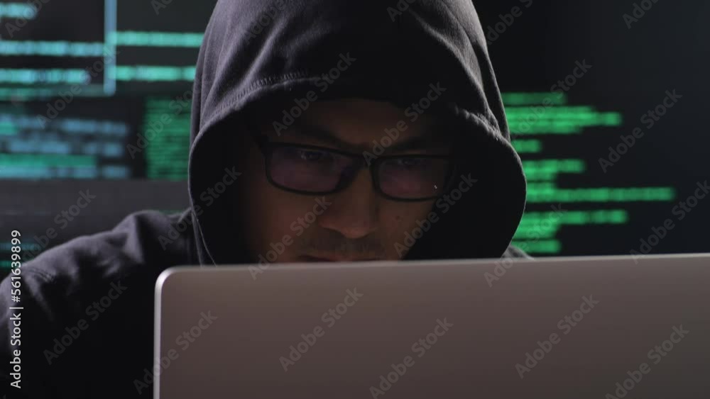 Close Up Of Asian Male Hacker In A Hood Works On A Laptop With Maps And Data On Display Screens Of Multiple Monitors In A Dark Office Room
Close Up Of Asian Male Hacker In A Hood Works On A Laptop With Maps And Data On Display Screens Of Multiple Monitors In A Dark Office Room