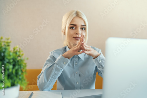 Young beautiful blonde businesswoman or college student works on laptop at home or in office. Online seminar, distance learning or job concept.
