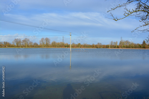 A utility pole is under water on a flooded field after heavy rainfall . Rural Oxfordshire in winter. 