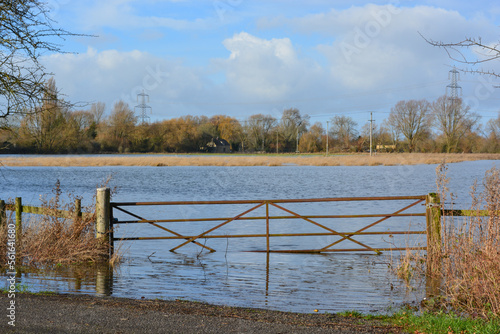 A view on a flooded field in rural Oxfordshire in winter. A gate to the farmland is under water after heavy rainfall.	