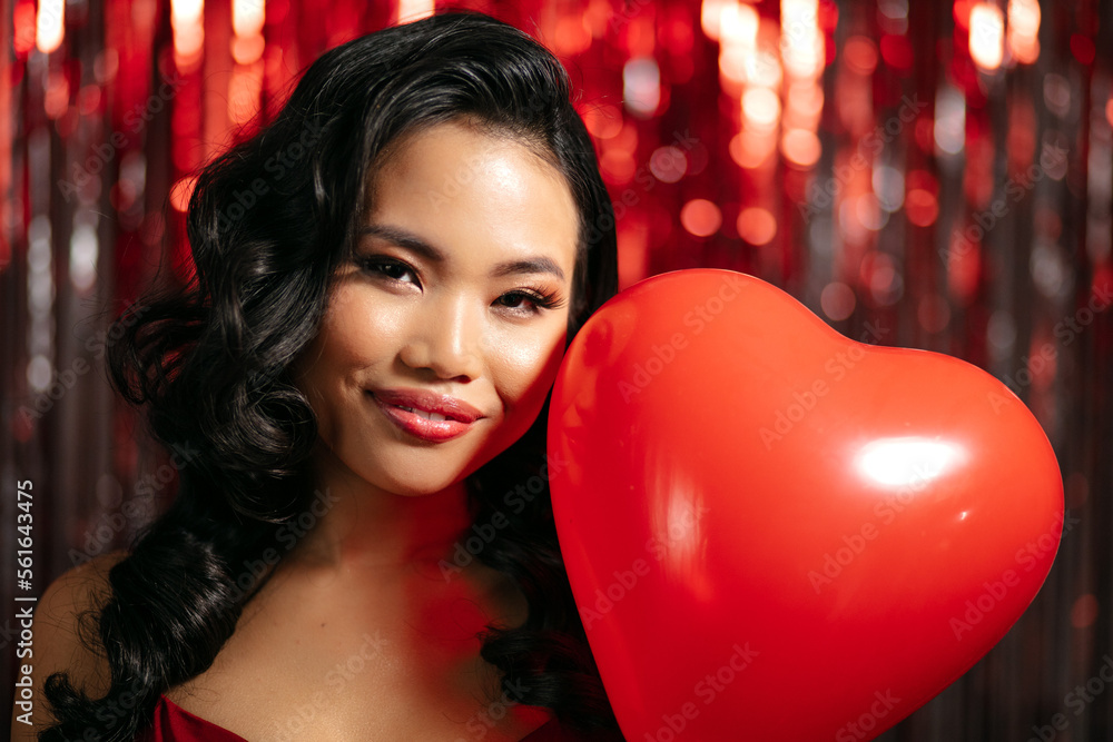 Young Beautiful Woman Posing With Heart-Shaped Balloon Over Shiny Red Background. Young Beautiful Woman Posing With Heart-Shaped Balloon Over Shiny Red Background.