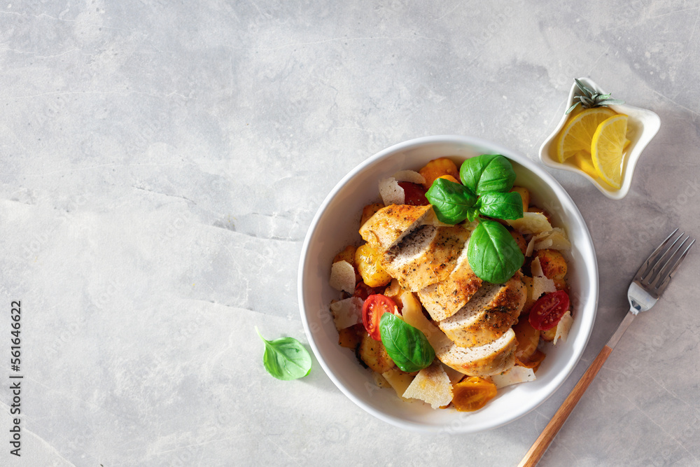 Dinner plate with potato gnocchi, tomatoes and grilled chicken breast on a light background. Italian food concept Dinner plate with potato gnocchi, tomatoes and grilled chicken breast on a light background. Italian food concept