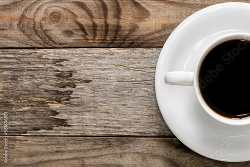 Cup of a dark coffee with a saucer on a wooden background, flat lay, copy space.