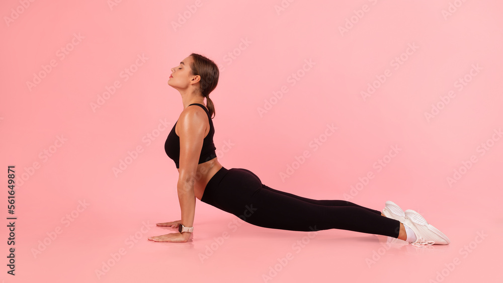Sporty young woman practicing yoga indoors, making upward facing dog pose Sporty young woman practicing yoga indoors, making upward facing dog pose