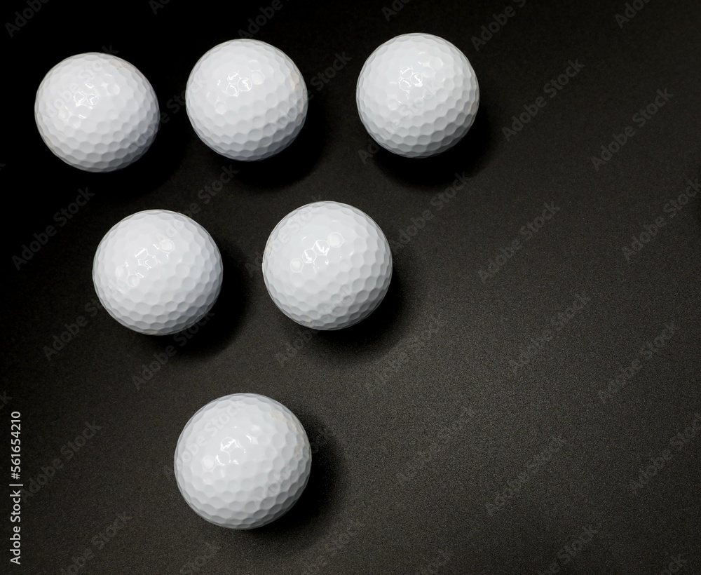 white golf balls in a triangle pattern on a classic black background white golf balls in a triangle pattern on a classic black background