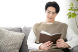 Asian man reading a book in the living room (room)　