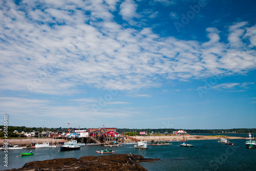 A red building on the edge of a small harbor with boats floating on a sunny day. photo