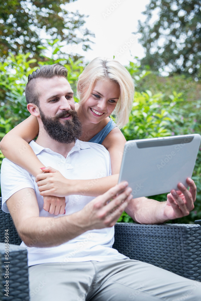 Happy young couple taking a selfie with digital tablet in garden, Bavaria, Germany Happy young couple taking a selfie with digital tablet in garden, Bavaria, Germany