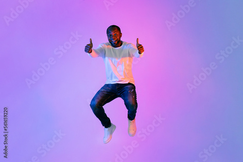 Emotional african american man showing thumb ups on colorful background