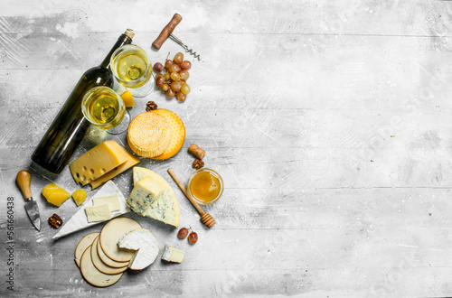 Assortment of types of cheese with white wine and honey.