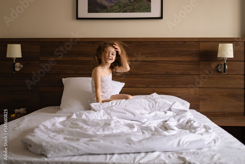 little funny shaggy girl playing with fighting pillow on the bed in the morning.