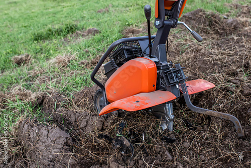 Cultivator in an uncultivated field in the spring. Virgin land with grass and weeds in the garden before plowing with a cultivator.