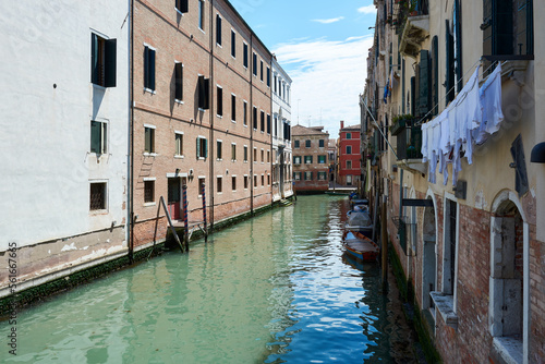 Beautiful, tranquil view in Venice, Italy, with boats parked on canal surrounded by picturesque old buildings under blue sky on spring day. © Eduardo Accorinti