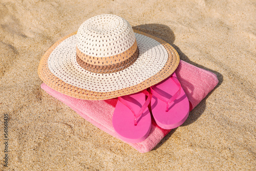 Beach towel with straw hat and slippers on sand