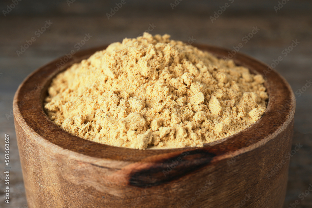 Bowl of mustard powder on wooden table, closeup Bowl of mustard powder on wooden table, closeup
