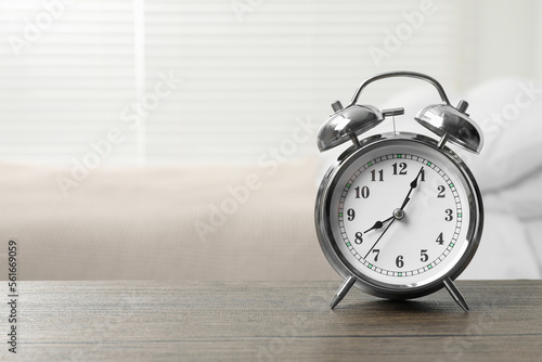 Silver alarm clock on wooden table in bedroom, space for text