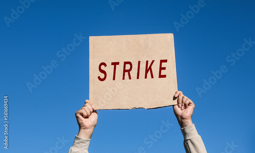 Young woman holding Strike sign against blue sky, closeup