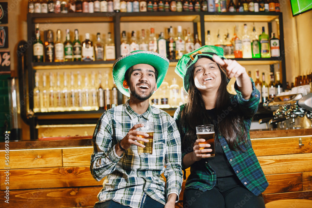 Obraz premium Indian friends celebrate St. Patrick's Day in a pub