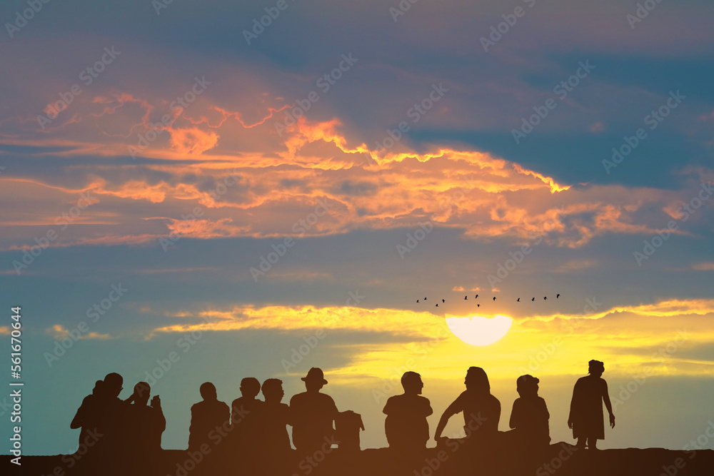 Silhouette people sitting on the floor and sunset on the colorful sky orange cloud and birds flying