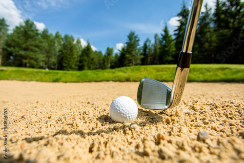 Golf ball in the sand, putter on a background.