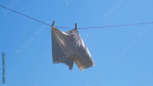 vintage white knickers are drying on a rope against the sky, swaying in the wind. slow motion.