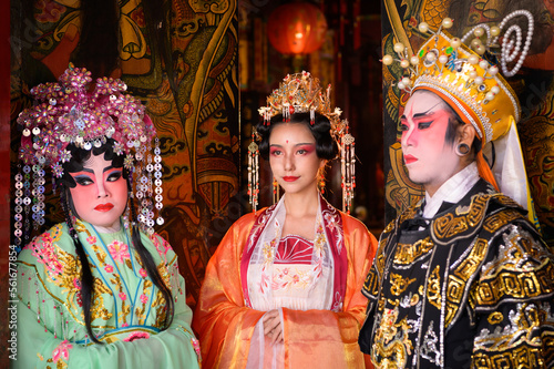 Portrait of male and female opera performers at the entrance to a sacred shrine or temple, praying for blessings on the occasion of the annual Chinese New Year.
