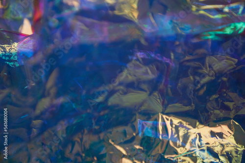 Holographic uneven, crumpled mother-of-pearl foil. Holographic iridescent abstract foil background. Unfocused background in blue tones. High quality photo