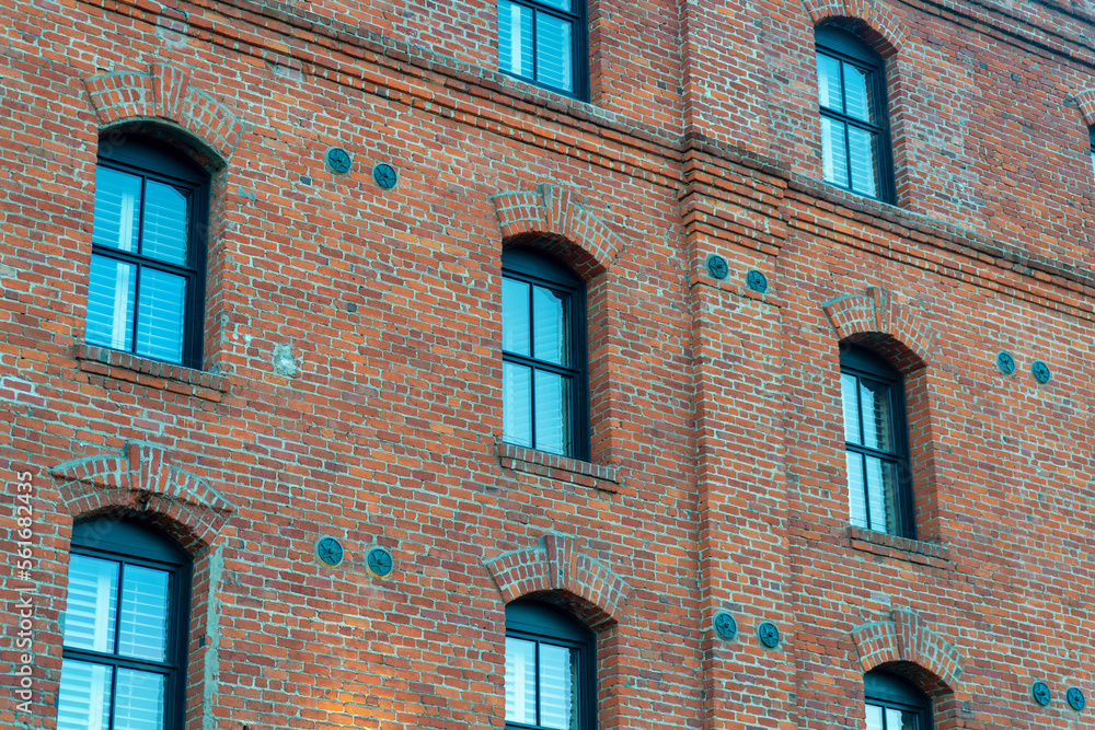 Obraz premium Non descript brick building with visible blue glass windows in afternoon shade in the business districts downtown