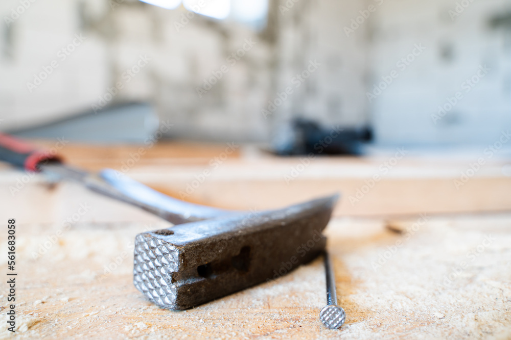 Roofing hammer with a nail close-up on a wooden surface on a blurred background Roofing hammer with a nail close-up on a wooden surface on a blurred background