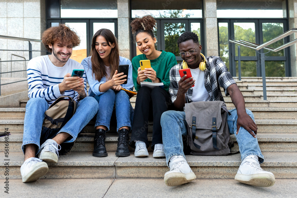 Fototapeta premium Multiracial college student friends look mobile phone laughing together. University students using smartphone outdoors.