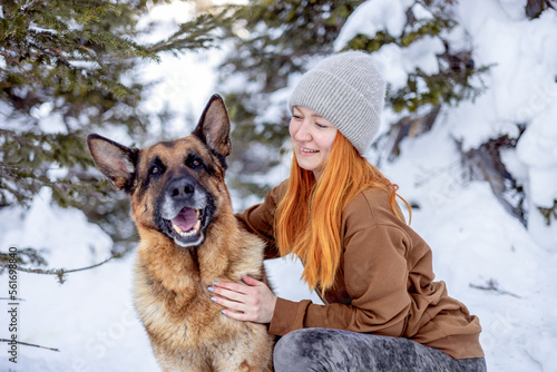 Fototapet Close-up of a young pretty woman with red hair and a German shepherd outdoors