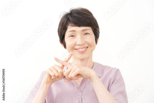 指でばつ印をする中年女性 白背景