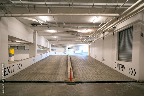 A concrete vehicle ramp inside a building with entry and exit signs