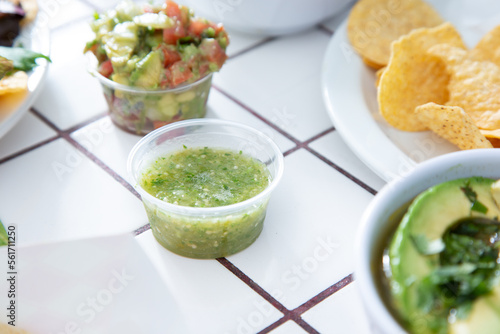 A view of a condiment cup of green salsa, or salsa verde.