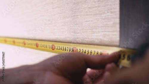 measuring the wall with a tape measure.