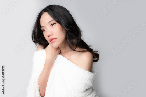 Asian beautiful woman cover with white fur blanket and show skin is looking away with thoughtful . Mental heathy or skin care and beauty concept