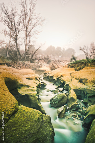 Stream of silky water between rocks on a misty winter morning. photo