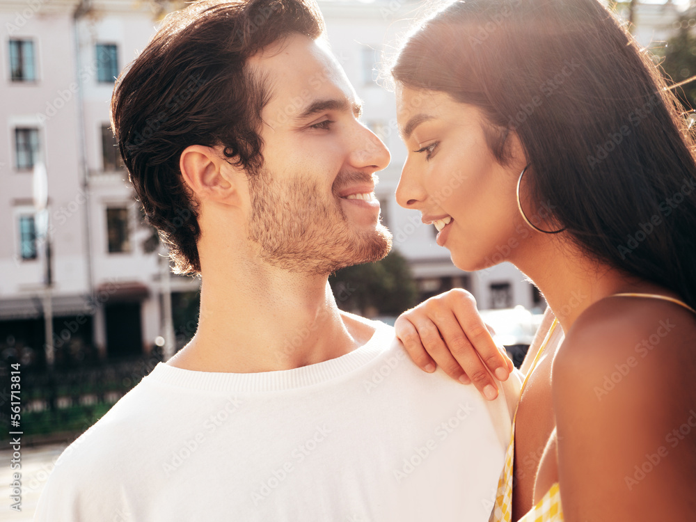 Naklejka premium Smiling beautiful woman and her handsome boyfriend. Happy cheerful family. Sexy couple posing in the street at sunrise. During romantic date at sunny summer day outdoors. Looking at each other