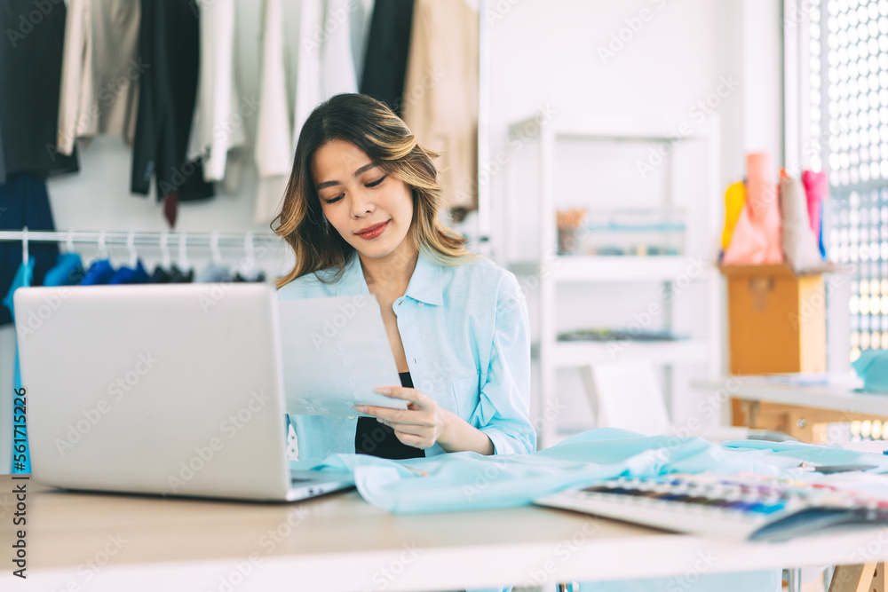 Young adult asian woman tailor designer using laptop computer for internet online marketing contact customer Young adult asian woman tailor designer using laptop computer for internet online marketing contact customer